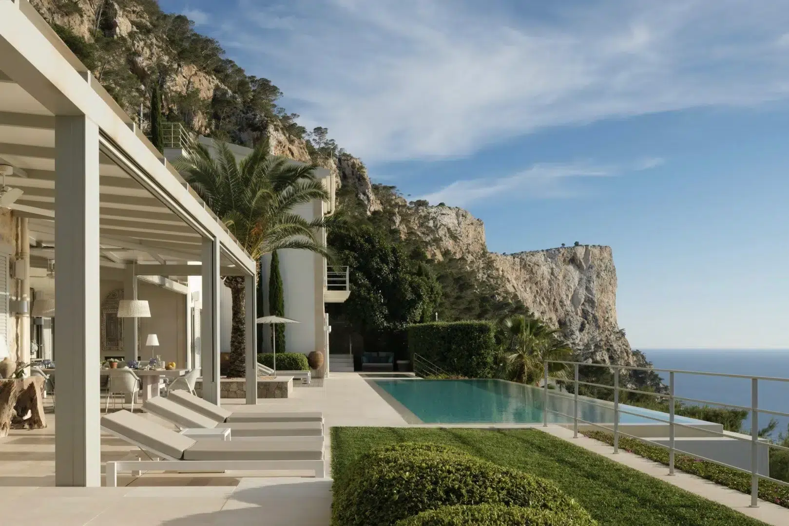 Luxury villa with pool overlooking the shimmering sea and coastal landscape.