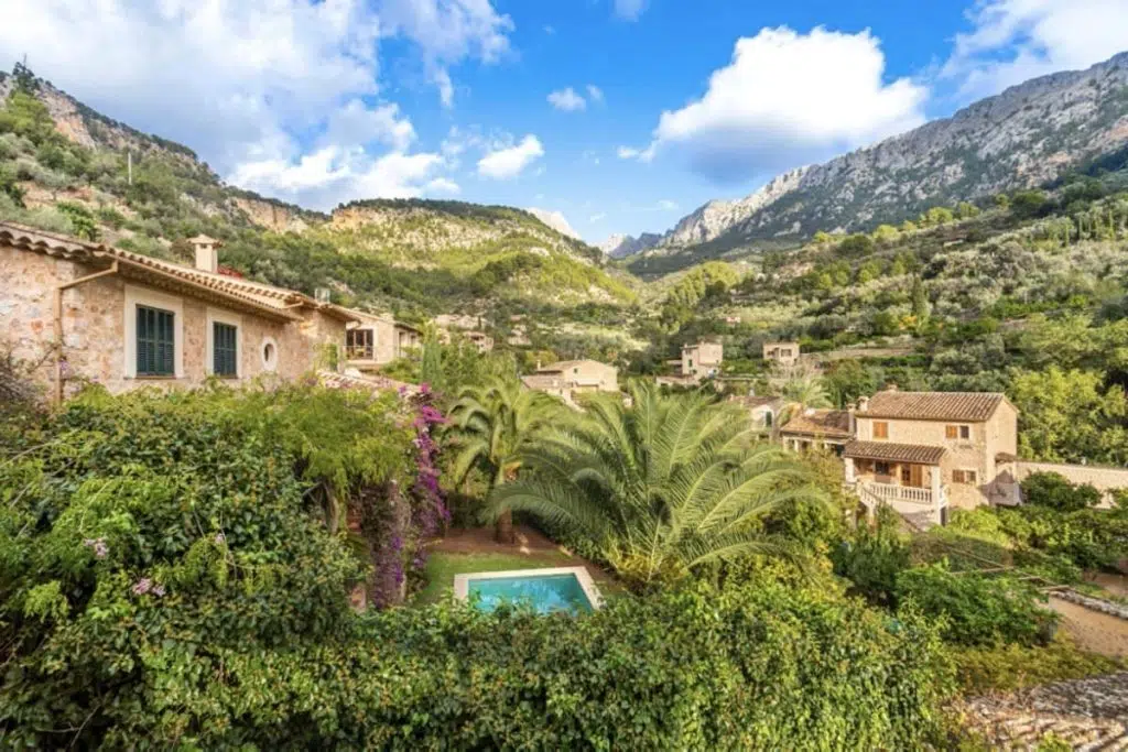 Villa Circe in Fornalutx, Mallorca, surrounded by stone houses, lush greenery and palm trees, with a private pool and panoramic Tramuntana mountain views.
