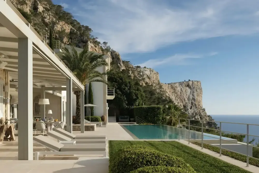 Luxury villa with pool overlooking the shimmering sea and coastal landscape.