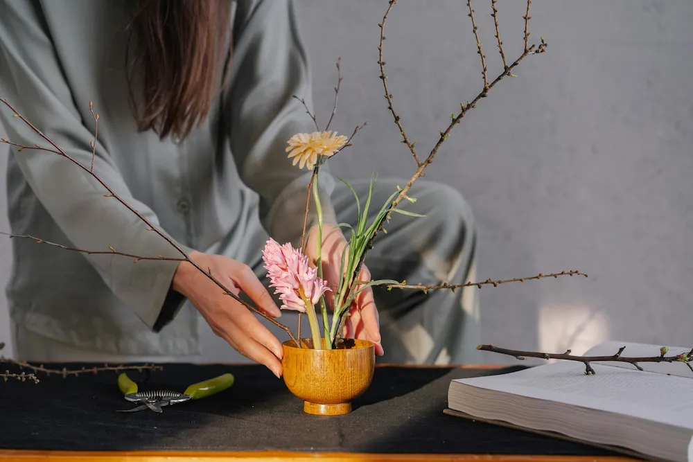 Villa concierge arranging fresh flowers in a wooden vase, creating a simple but thoughtful detail that reflects authentic Mallorca experiences.