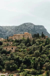 View of Deià Mallorca villas nestled in the Tramuntana mountains, surrounded by olive groves and stone terraces.