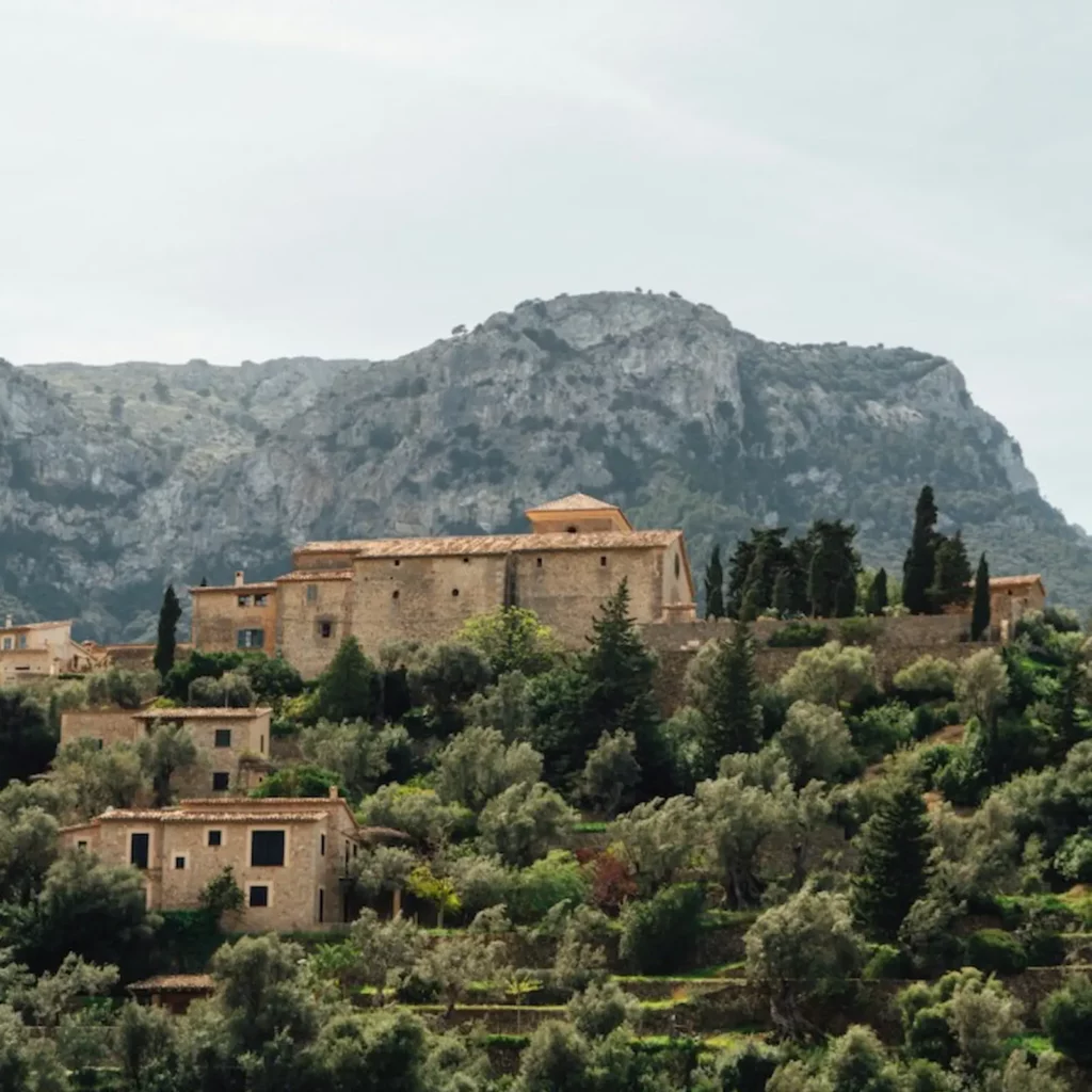 View of Deià Mallorca villas nestled in the Tramuntana mountains, surrounded by olive groves and stone terraces.