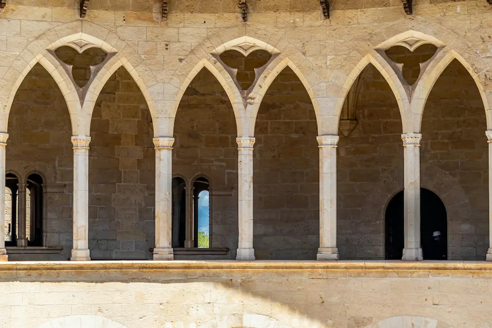 Arcos góticos del Castillo de Bellver, en Mallorca, construidos con la tradicional arenisca de marés, una influencia histórica en el estilo de restauración de las fincas de lujo de Mallorca.