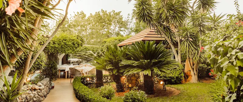 Garden dining area at Restaurante Jardín in Alcúdia, Mallorca, set within a lush Mediterranean outdoor setting.