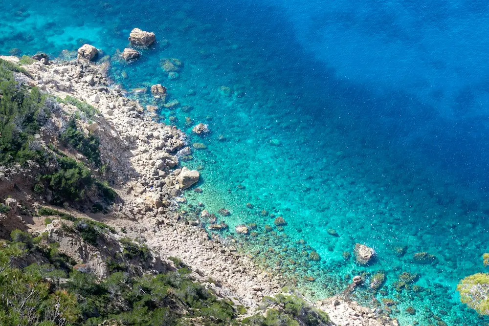 Aerial view of Sant Elm’s rocky coastline and crystal-clear turquoise water in southwest Mallorca, showcasing one of the top beaches near Port d’Andratx.